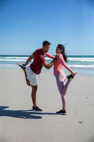 Diverse Couple Stretching on Sunny Beach Promoting Fitness and Wellness