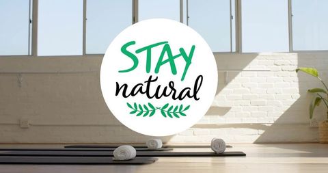 Sunlit minimalist yoga studio interior featuring stay natural logo decal, mats, rolled towels