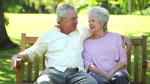 Cheerful Retired Couple Relaxing on Park Bench