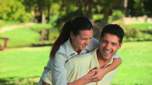 Couple enjoys a playful moment outside, highlighting joy and companionship in a natural setting. Ideal for promoting relationships, happiness, outdoor activities, and leisure time.