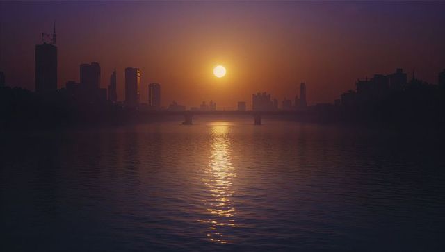 Sunlit urban river with silhouette skyline