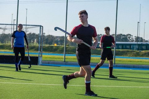 Young Males Playing Field Hockey on Outdoor Turf