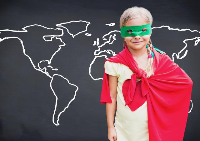 Little girl dressed as a superhero with red cape and green eye mask standing against a world map background. Perfect for use in educational materials, children's books, or articles on child development and imaginative play. Bright and colorful image showcasing youth empowerment and creativity.