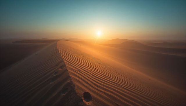 Golden sands bathed in sunrise across desert dunes