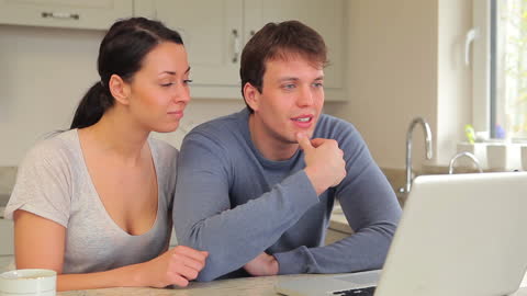 Couple Discussing and Analyzing Online Content in Kitchen