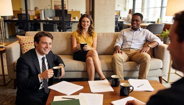 Team reviewing documents over coffee in casual office lounge