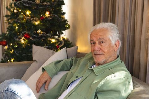 Senior Man Relaxing at Home by Christmas Tree