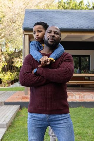 African american father carrying son on shoulders backyard bonding and protection
