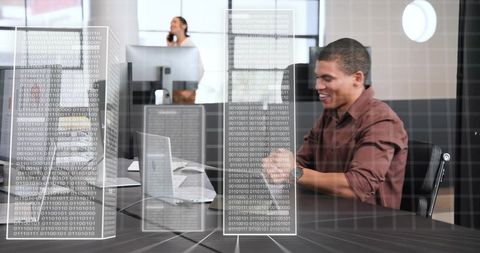 Man typing on laptop in modern office with holographic binary servers and digital data