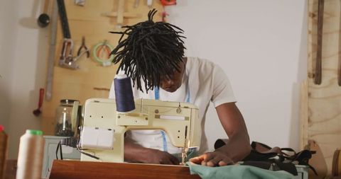 Craftsman sewing leather in workshop with vintage machine