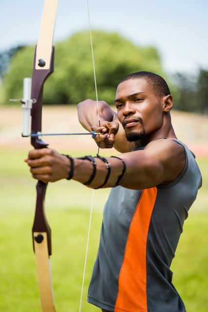 Athlete practicing archery in an outdoor stadium, focusing on target with bow and arrow. Ideal for use in sports training materials, fitness and health promotions, archery clubs, and motivational content related to precision and concentration.