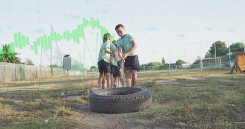 Children strength training with tractor tire outdoors