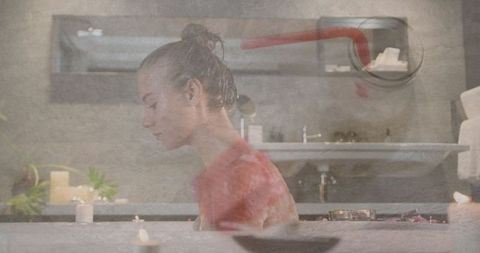 Woman relaxing in spa-like bathroom with lit candles