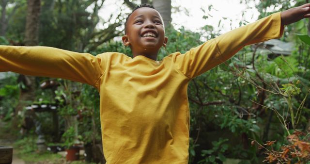 Happy african american boy running and playing in garden. Spending time outdoors, working in garden nursery.