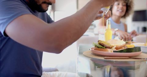 Friends dining healthy burgers adding condiment