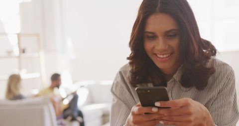 Smiling Woman Using Smartphone with Friends in Background - Download Free Stock Images Pikwizard.com
