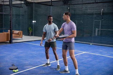 Indoor padel coaching with diverse male athletes on blue court practicing paddle drills