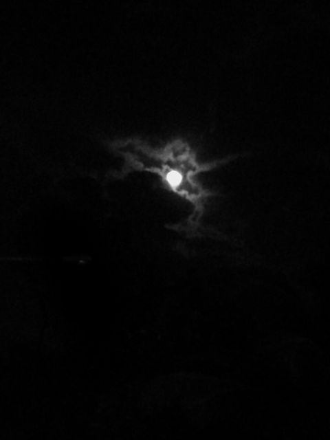Full moon glowing behind partially covering clouds during night time, creating an eerie and mysterious scene. Perfect for themes related to nature, astronomy, night time, or eerie and mysterious atmospheres.