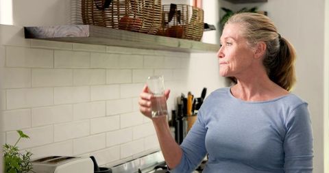 Senior Woman in Kitchen Drinking Water for Wellness