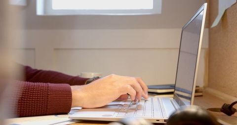 Person typing on laptop in cozy home workspace
