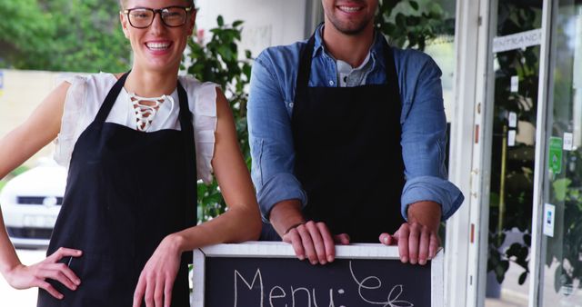 Smiling waiter and waitress standing with menu board outside the cafe 4k