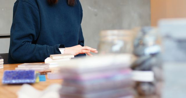 Person organizing documents on an office desk. Useful for themes related to productivity, business, workplace, and organizational skills. Great for illustrating professional environments and office tasks.