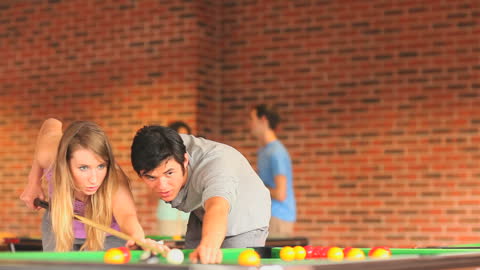 Couple Playing Pool Enthusiastically in Brick Interior