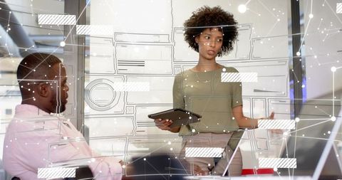 Businesswoman presenting with tablet and holographic interface during team meeting