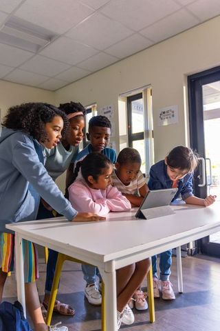 Diverse students collaborating around tablet, group learning and technology in classroom