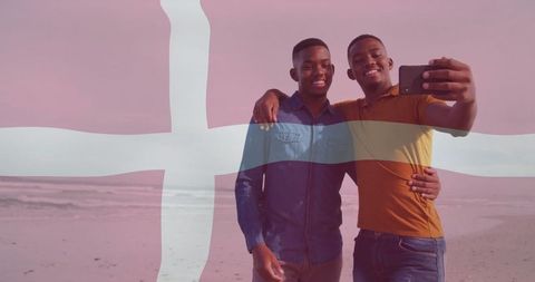 Two friends taking selfie on beach with danish flag overlay