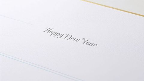 Embossed happy new year in silver foil on textured white card with gold border