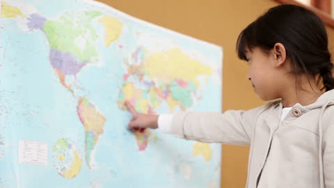 Young Girl Learning Geography by Pointing at World Map in Classroom