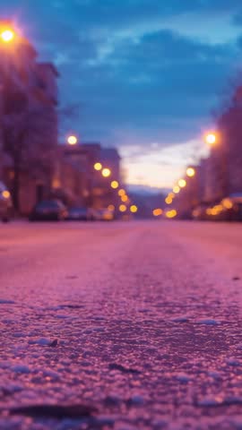 Vertical video capturing icy city street at dusk with glowing lamps and reflective frost