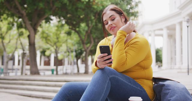 Young Woman Sitting Outdoors Engaging with Smartphone - Download Free Stock Images Pikwizard.com