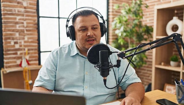 Male podcaster recording in bright industrial home studio speaking into microphone