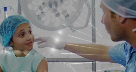 Pediatric clinician reaching and comforting young patient in surgical cap under operating light