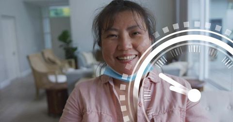 Smiling asian woman with mask under chin in bright lounge with speedometer overlay