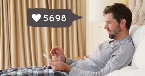 Man in Bed Using Smartphone with Social Media Notification