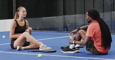 Players Relaxing on Court After Intense Padel Match with Sports Equipment