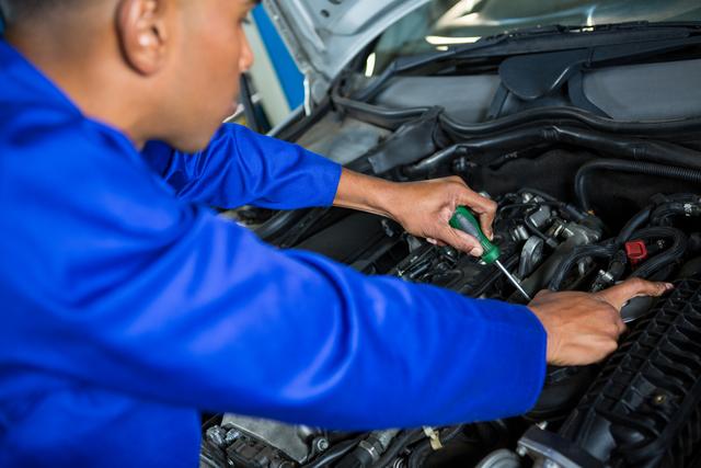 Attentive mechanic servicing automobile car engine in repair garage