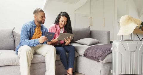 Couple Planning Vacation with Suitcase and Tablet at Home