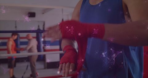 Male boxer wrapping hands with red wraps in ring preparing for sparring and training