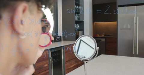 Man applying makeup while solving math equations reflected on glass in modern kitchen