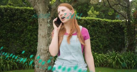 Casual young woman talking on smartphone in backyard with turquoise doodle accents
