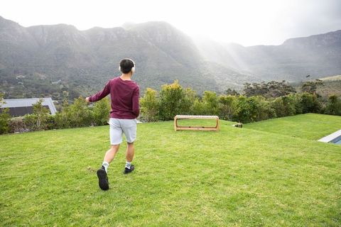Person walking on manicured lawn toward mountain view with wooden bench and pool edge