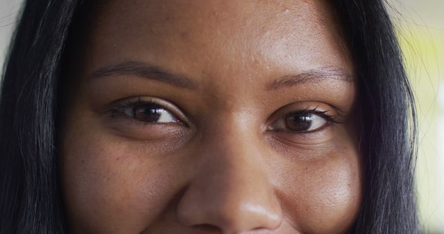 This image captures a detailed and close-up view of a woman's eyes with a warm expression. The focus on her brown eyes and natural skin tone highlights her beauty and expressive features. This can be used in contexts such as beauty and makeup advertising, personal care imagery, or empowering campaigns focusing on natural beauty. Ideal for blogs, websites, or magazines promoting self-confidence, skincare products, or emotional connection.