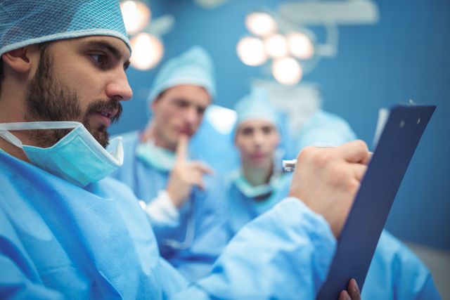 Team of surgeons having discussion over clipboard at hospital