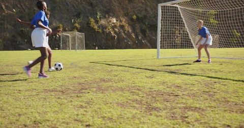 Female Youth Soccer Players Dribbling by Rocky Hillside