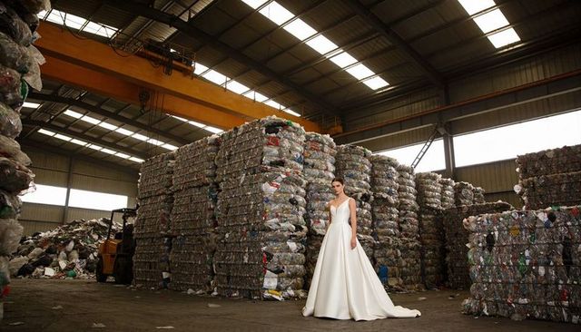 Bridal couture juxtaposing elegant wedding gown with industrial recycled plastic bales