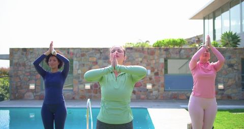 Diverse women practicing poolside yoga in long sleeve athletic tops for wellness